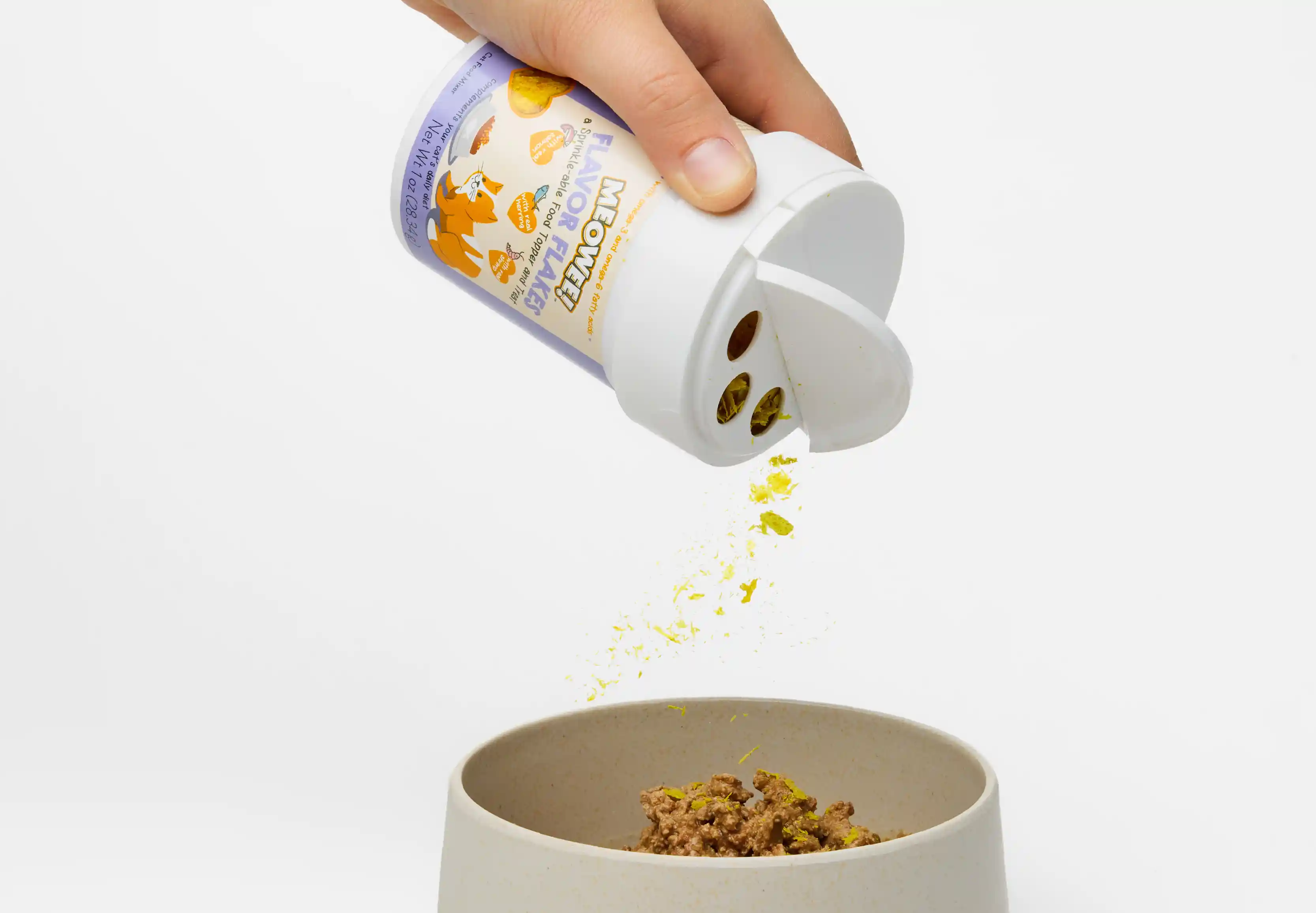 Woman shaking Meowee cat topper flakes onto cat food